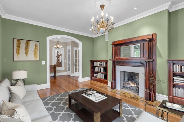 511 4th Ave, Asbury Park, NJ 07712 - living area with arched walkways, a chandelier, a fireplace with flush hearth, wood finished floors, and crown molding