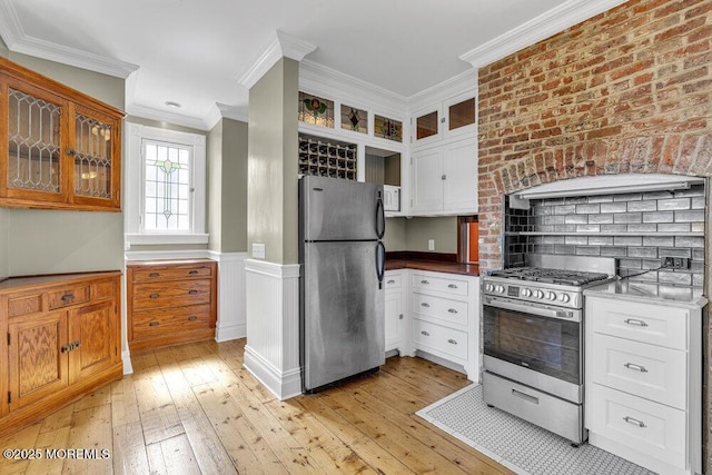 511 4th Ave, Asbury Park, NJ 07712 - kitchen with stainless steel appliances, ornamental molding, light wood finished floors, glass insert cabinets, and white cabinetry