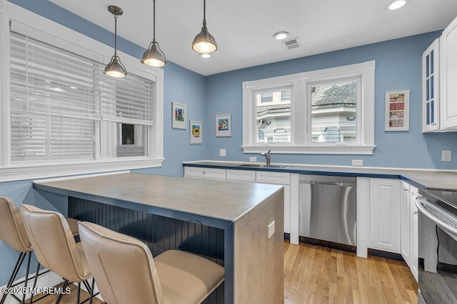 511 4th Ave, Asbury Park, NJ 07712 - kitchen featuring stainless steel appliances, a kitchen breakfast bar, white cabinets, light wood-style floors, and a sink