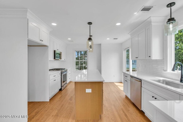 27 Main St, Port Monmouth, NJ 07758 - kitchen featuring appliances with stainless steel finishes, a sink, a center island, white cabinets, and light wood finished floors