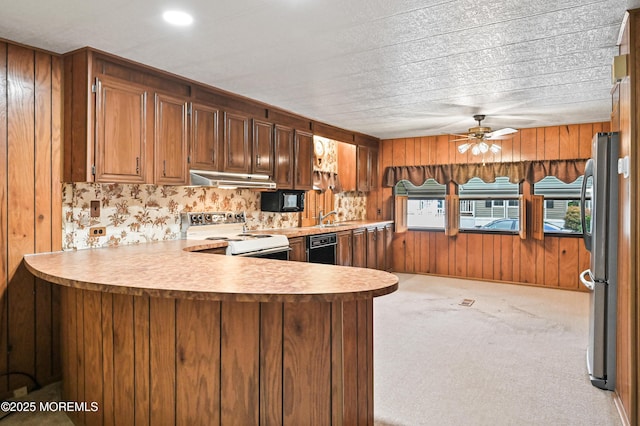 119 Village Rd, Morganville, NJ 07751 - kitchen featuring white electric stove, freestanding refrigerator, under cabinet range hood, black dishwasher, and wooden walls
