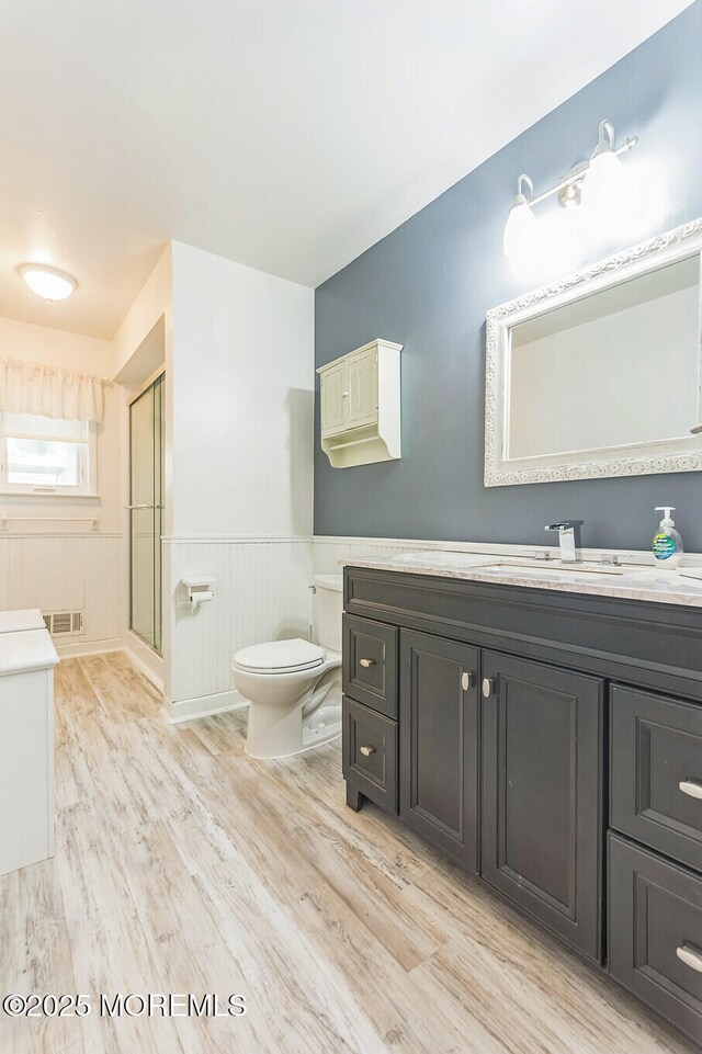 824 Broadway Blvd, Toms River, NJ 08757 - full bathroom with toilet, vanity, a stall shower, wood finished floors, and wainscoting
