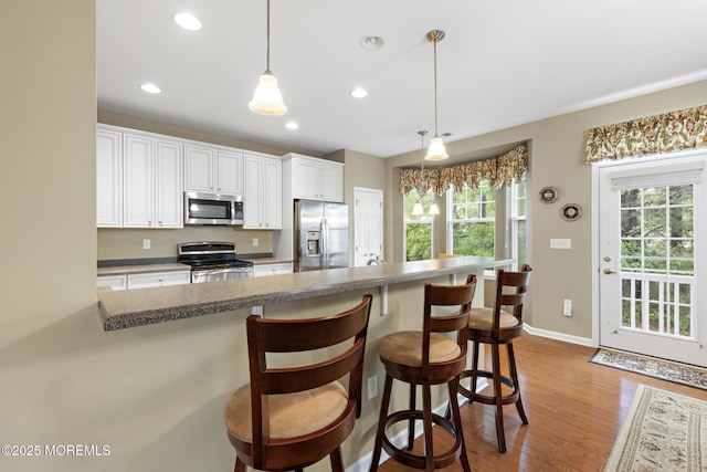 12 Stemson Ct, Little Egg Harbor, NJ 08087 - kitchen with appliances with stainless steel finishes, wood finished floors, white cabinets, a kitchen bar, and recessed lighting