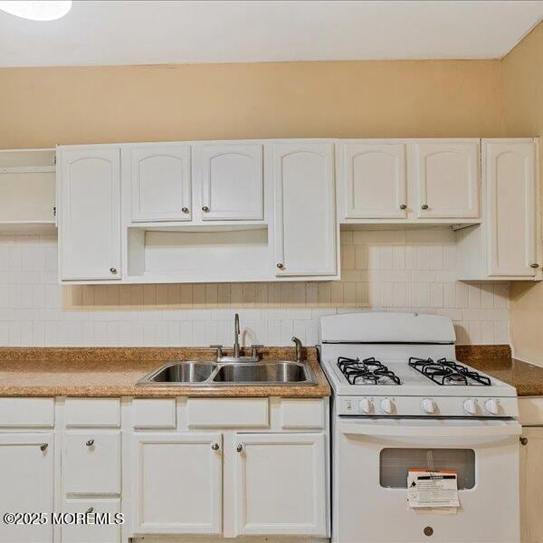 1262 Thurman St, Camden, NJ 08104 - kitchen with white range with gas cooktop, a sink, white cabinets, and decorative backsplash