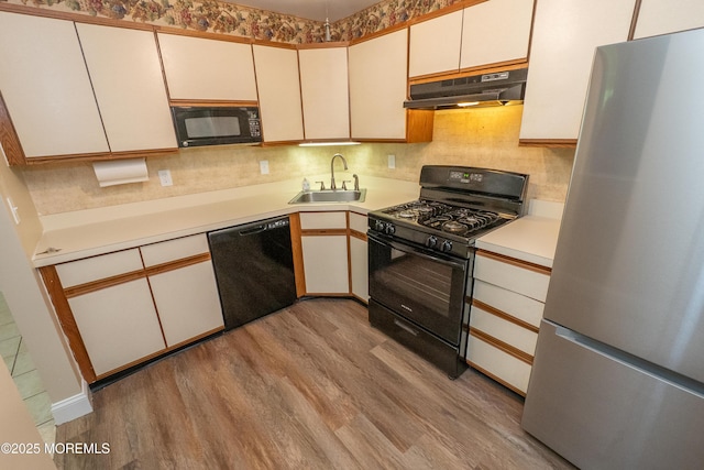 2708 Ridgefield Ct Unit 2708, Helmetta, NJ 08828 - kitchen featuring black appliances, under cabinet range hood, a sink, light wood-style flooring, and light countertops