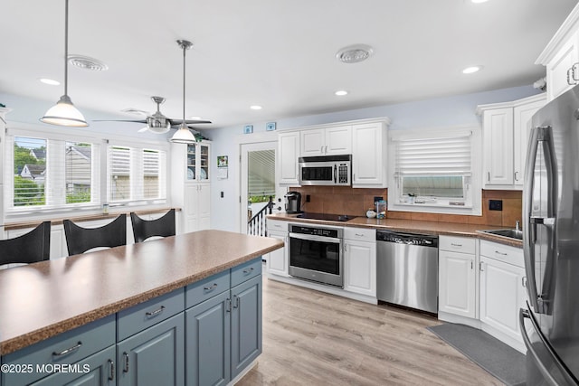 660 Summit Ave, Kenilworth, NJ 07033 - kitchen with stainless steel appliances, white cabinets, decorative backsplash, hanging light fixtures, and a ceiling fan