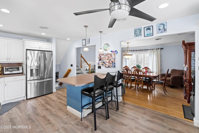 660 Summit Ave, Kenilworth, NJ 07033 - kitchen with stainless steel fridge, a breakfast bar area, ceiling fan, white cabinetry, and light wood-style floors