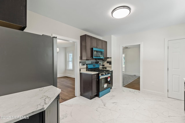 23 Stokes St, Freehold, NJ 07728 - kitchen with stainless steel appliances, light marble finish floors, dark brown cabinets, and baseboards