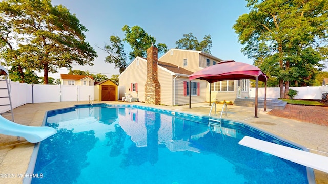 933 Chelsea St, Forked River, NJ 08731 - view of pool with a water slide, a patio, a diving board, a fenced backyard, and a storage shed