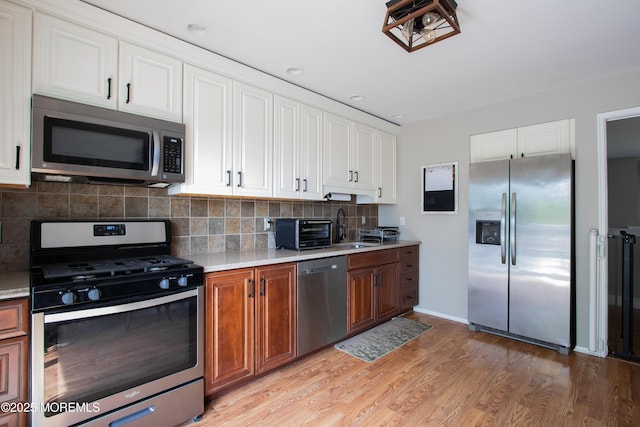 20 Koosman Dr, Leonardo, NJ 07737 - kitchen with stainless steel appliances, light countertops, white cabinets, tasteful backsplash, and light wood-style flooring