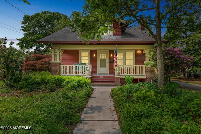 228 Albert Pl, Elberon, NJ 07740 - bungalow-style home with covered porch, a chimney, roof with shingles, and brick siding
