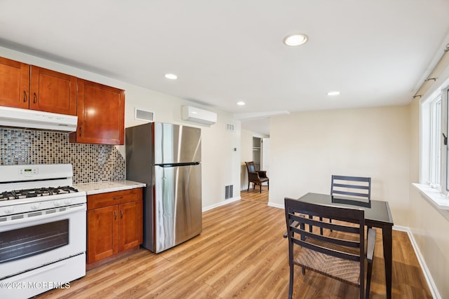 228 Albert Pl, Elberon, NJ 07740 - kitchen featuring white range with gas stovetop, under cabinet range hood, freestanding refrigerator, a wall mounted air conditioner, and light wood-style floors