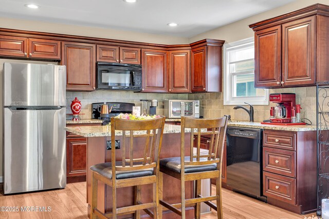 87 Prince Charles Dr, Toms River, NJ 08757 - kitchen with black appliances, light wood-style floors, light stone counters, backsplash, and recessed lighting