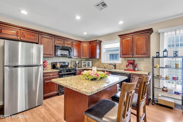 87 Prince Charles Dr, Toms River, NJ 08757 - kitchen with black appliances, light wood-style floors, a breakfast bar area, a sink, and recessed lighting