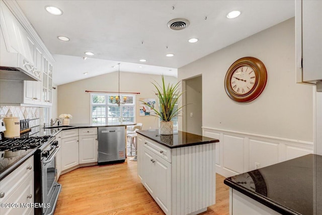 635 Susan Ln, Brielle, NJ 08730 - kitchen with appliances with stainless steel finishes, light wood-type flooring, white cabinetry, a wainscoted wall, and lofted ceiling