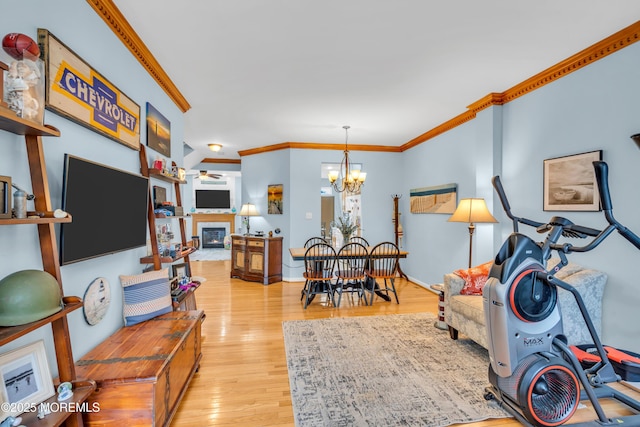 18 Skimmer Ln Unit 53, Bayville, NJ 08721 - living room with crown molding, light wood-style floors, a chandelier, a glass covered fireplace, and ceiling fan