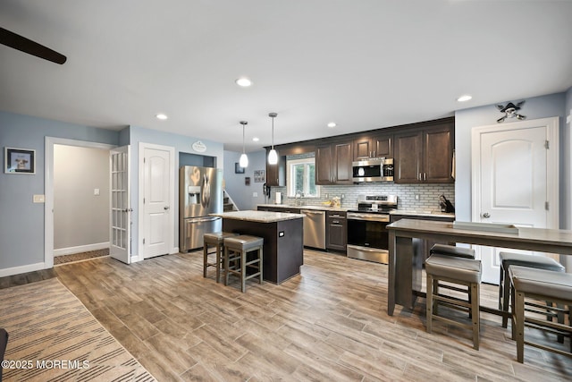 41 Revere Pl, Freehold, NJ 07728 - kitchen with appliances with stainless steel finishes, dark brown cabinets, a kitchen bar, a center island, and decorative backsplash