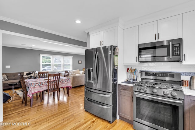 18 Delaware Ave, West Long Branch, NJ 07764 - kitchen featuring appliances with stainless steel finishes, crown molding, white cabinetry, light wood finished floors, and light countertops