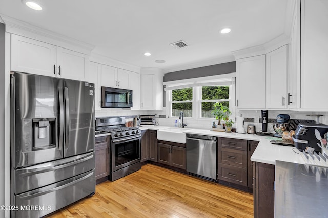 18 Delaware Ave, West Long Branch, NJ 07764 - kitchen with stainless steel appliances, tasteful backsplash, light countertops, white cabinetry, and light wood finished floors