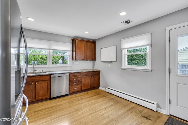 20 Delaware Ave, West Long Branch, NJ 07764 - kitchen featuring appliances with stainless steel finishes, a baseboard heating unit, light stone counters, light wood finished floors, and brown cabinets