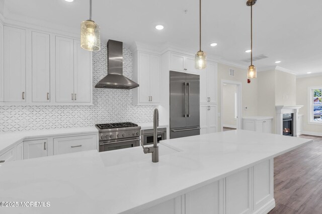 34 Broad St Unit 306, Manasquan, NJ 08736 - kitchen featuring premium appliances, wall chimney exhaust hood, white cabinetry, decorative backsplash, and wood finished floors
