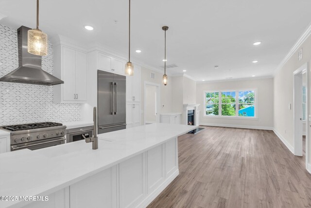 34 Broad St Unit 306, Manasquan, NJ 08736 - kitchen with premium appliances, wall chimney exhaust hood, ornamental molding, white cabinets, and decorative backsplash