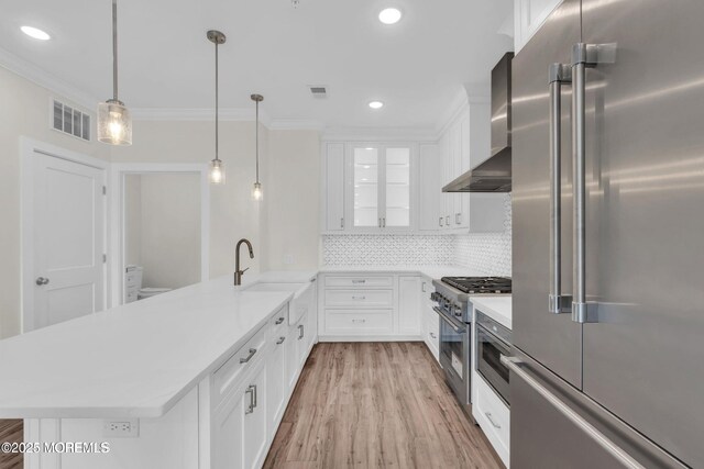 34 Broad St Unit 306, Manasquan, NJ 08736 - kitchen featuring premium appliances, wall chimney exhaust hood, crown molding, a peninsula, and light countertops