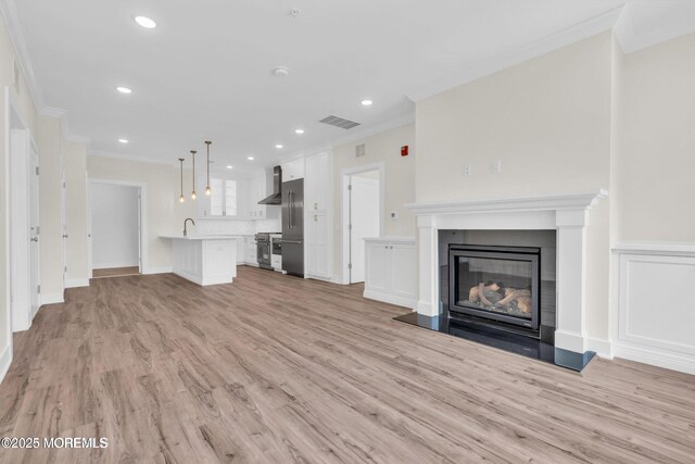 34 Broad St Unit 306, Manasquan, NJ 08736 - unfurnished living room featuring crown molding, light wood-type flooring, a sink, a glass covered fireplace, and recessed lighting