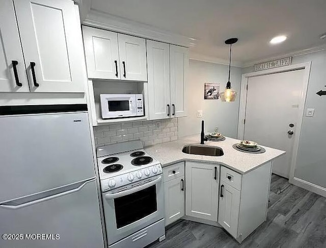 225 E Wildwood Ave # 323, Wildwood, NJ 08260 - kitchen featuring white appliances, a sink, a peninsula, white cabinetry, and dark wood-type flooring