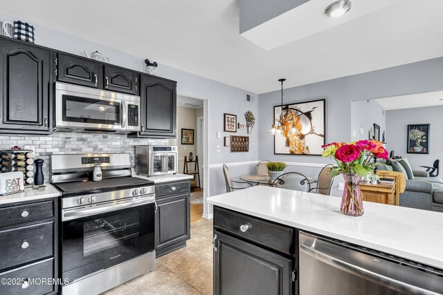 28 Mansfield Ave, Manchester, NJ 08759 - kitchen featuring stainless steel appliances, light countertops, tasteful backsplash, light tile patterned flooring, and hanging light fixtures