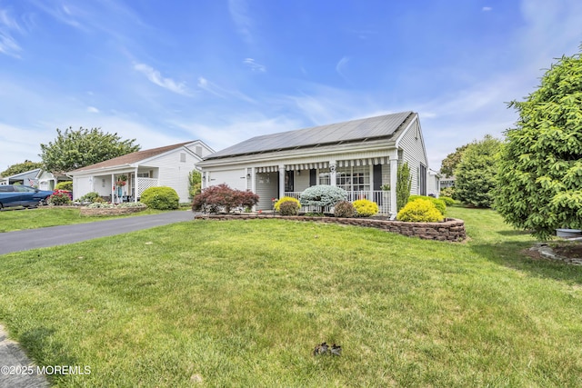 28 Mansfield Ave, Manchester, NJ 08759 - view of front of house with covered porch, a garage, a front lawn, roof mounted solar panels, and asphalt driveway