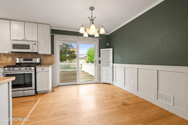 183 Crestview Dr, Middletown, NJ 07748 - kitchen with white microwave, stainless steel gas range oven, crown molding, a chandelier, and white cabinets
