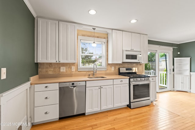 183 Crestview Dr, Middletown, NJ 07748 - kitchen with stainless steel appliances, a sink, crown molding, white cabinets, and light wood-style floors