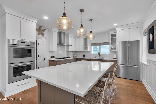 8 W St, Rumson, NJ 07760 - kitchen with appliances with stainless steel finishes, wall chimney exhaust hood, a breakfast bar area, glass insert cabinets, and white cabinets