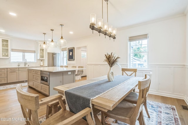 8 W St, Rumson, NJ 07760 - dining space featuring a decorative wall, ornamental molding, a wainscoted wall, light wood finished floors, and a chandelier