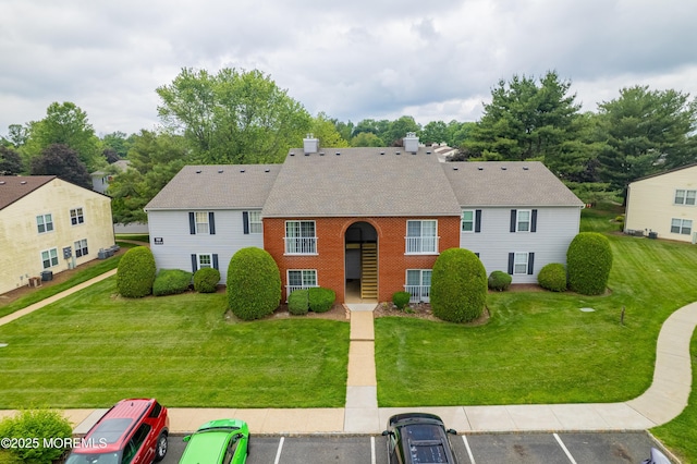 717 Zlotkin Cir Unit 1, Freehold, NJ 07728 - view of front of home with uncovered parking, a front lawn, brick siding, and a shingled roof