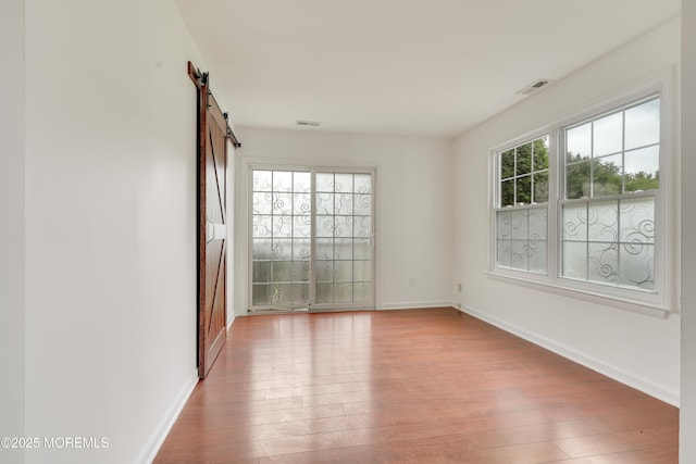 717 Zlotkin Cir Unit 1, Freehold, NJ 07728 - empty room featuring a barn door, hardwood / wood-style floors, and baseboards