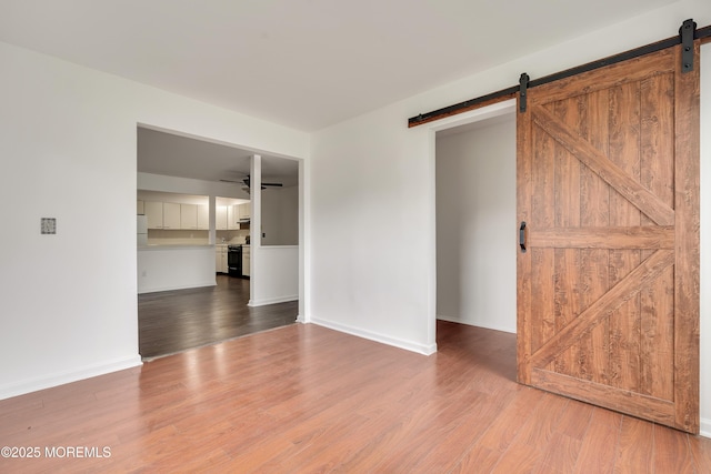 717 Zlotkin Cir Unit 1, Freehold, NJ 07728 - empty room with a barn door, wood finished floors, baseboards, and ceiling fan