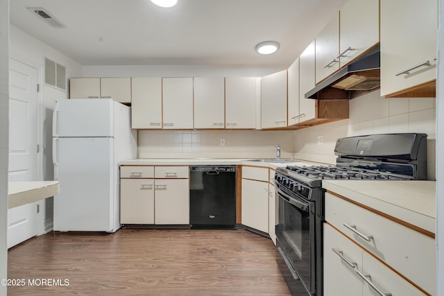 717 Zlotkin Cir Unit 1, Freehold, NJ 07728 - kitchen with black appliances, under cabinet range hood, a sink, light countertops, and dark wood-style flooring