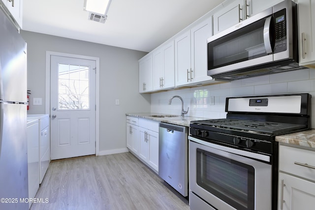 68 Elm St, Beachwood, NJ 08722 - kitchen with stainless steel appliances, washing machine and dryer, a sink, backsplash, and light wood finished floors