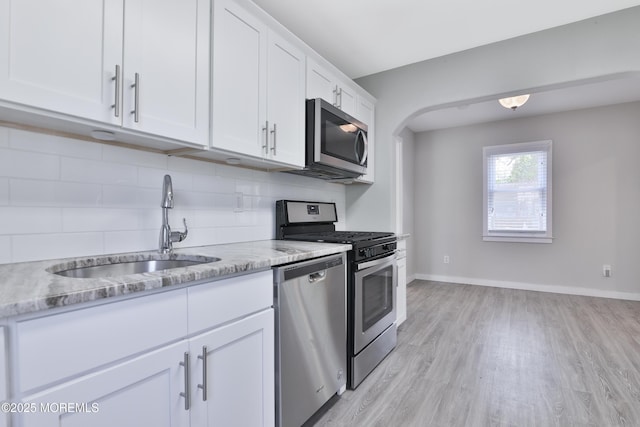 68 Elm St, Beachwood, NJ 08722 - kitchen featuring appliances with stainless steel finishes, a sink, decorative backsplash, light wood finished floors, and white cabinets
