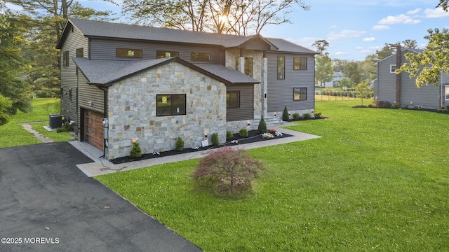 4 Penny Ct, East Brunswick, NJ 08816 - view of front of house featuring stone siding, driveway, roof with shingles, a front lawn, and cooling unit