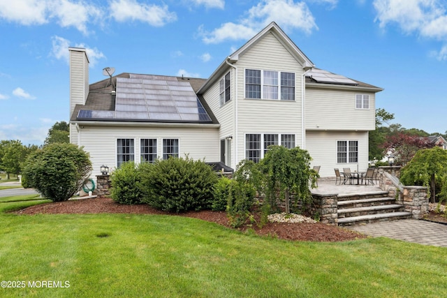 7 Topaz Dr, Jackson, NJ 08527 - back of house with roof mounted solar panels, a lawn, a patio, and a chimney