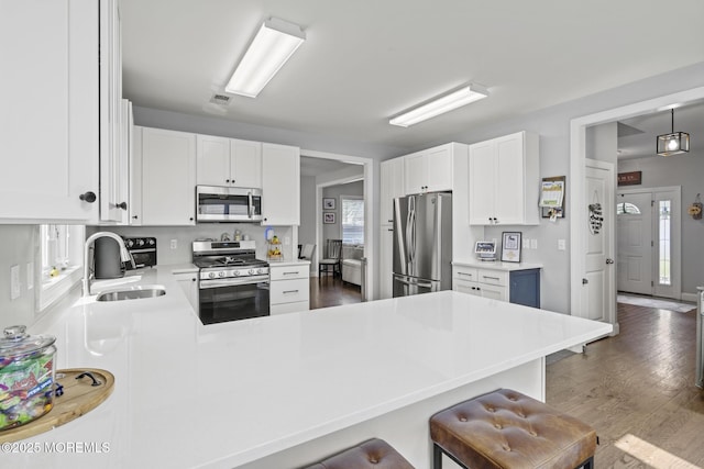 62 E 5th St, Howell, NJ 07731 - kitchen with stainless steel appliances, a sink, a peninsula, a breakfast bar area, and white cabinets