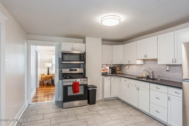 147 Joseph St, East Brunswick, NJ 08816 - kitchen with appliances with stainless steel finishes, tasteful backsplash, white cabinetry, dark countertops, and light wood-style floors