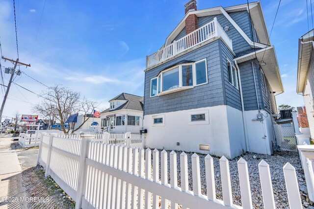 1204 River Rd, Belmar, NJ 07719 - view of side of home featuring a balcony, a fenced front yard, and a chimney