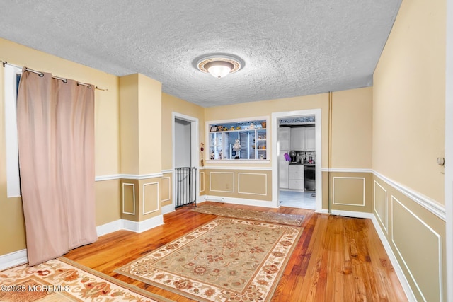 830 Atlantic City Blvd, Bayville, NJ 08721 - unfurnished bedroom featuring hardwood / wood-style floors, a decorative wall, a textured ceiling, wainscoting, and a closet