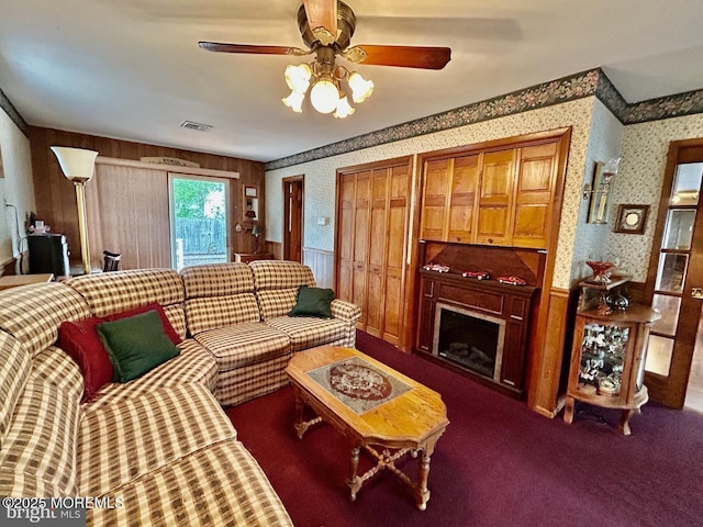 504 Windsor St, Forked River, NJ 08731 - carpeted living area featuring wallpapered walls, a wainscoted wall, a ceiling fan, a fireplace, and wood walls