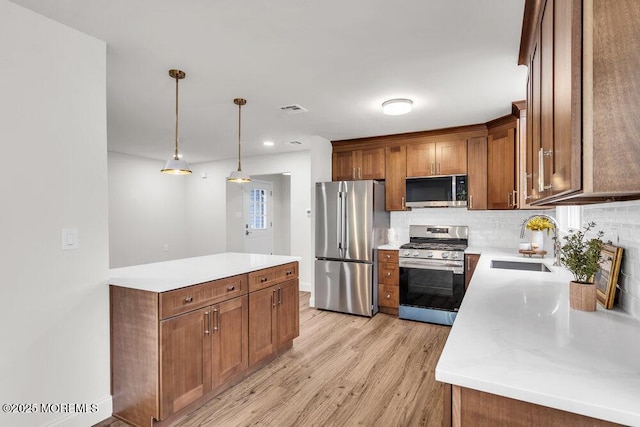 85 Central Blvd, Brick, NJ 08724 - kitchen with appliances with stainless steel finishes, a sink, brown cabinets, light wood-style flooring, and backsplash