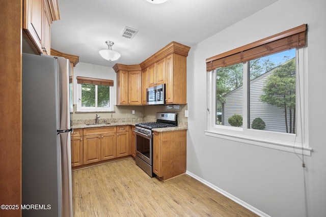 70 Lexington Cir, Matawan, NJ 07747 - kitchen with appliances with stainless steel finishes, light wood-type flooring, backsplash, light stone counters, and baseboards